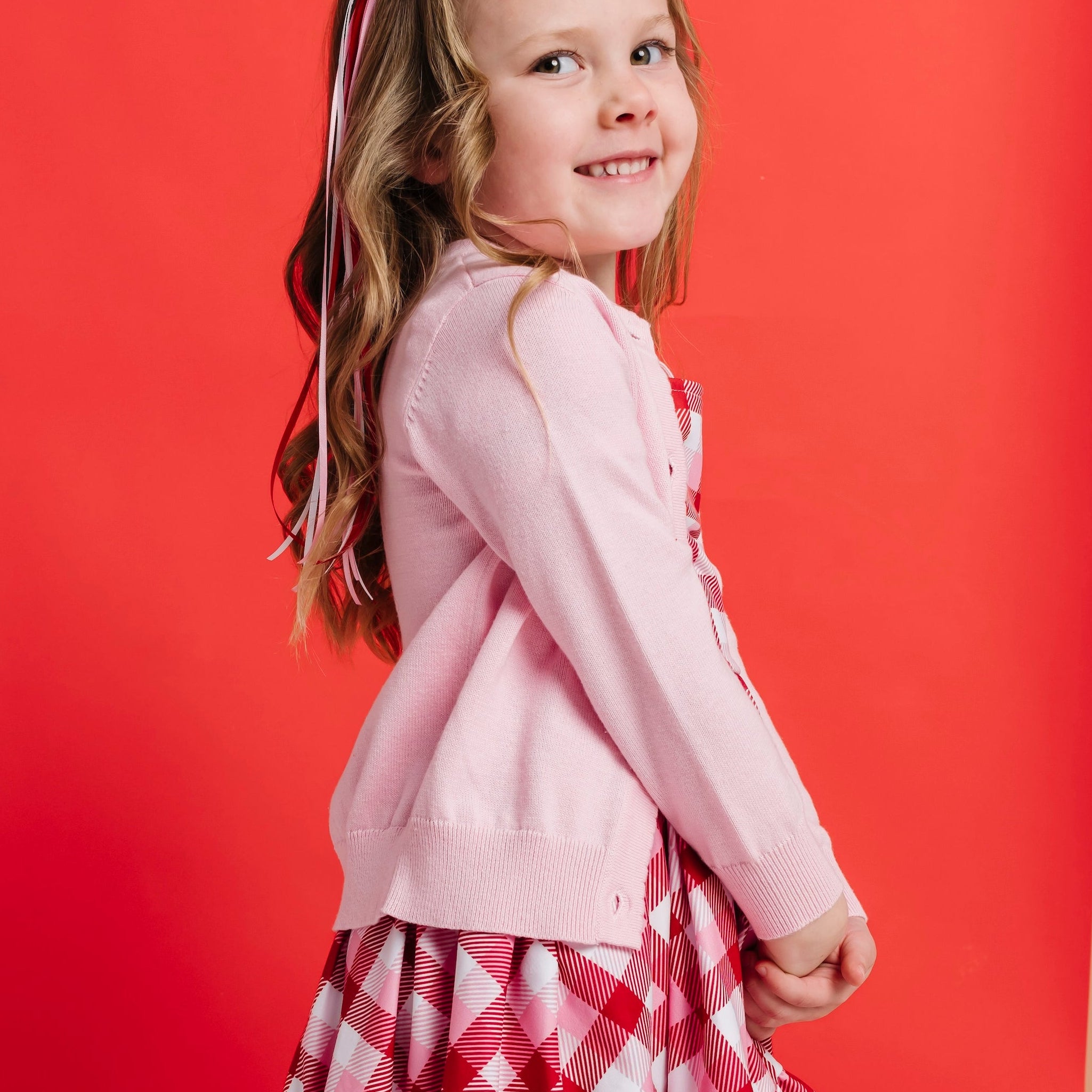 girl in valentine's day outfit of red and pink plaid twirl dress and blossom pink cardigan