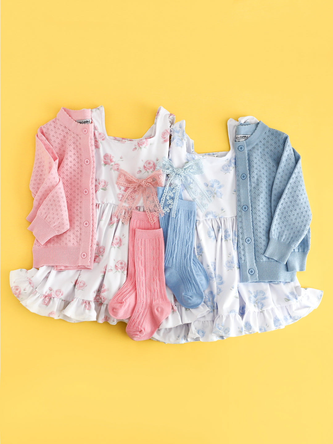 side by side flat lay of girl's white spring dresses with blossom and pastel blue floral prints paired with matching pointelle cardigans, cable knit knee high socks and lace hair bows