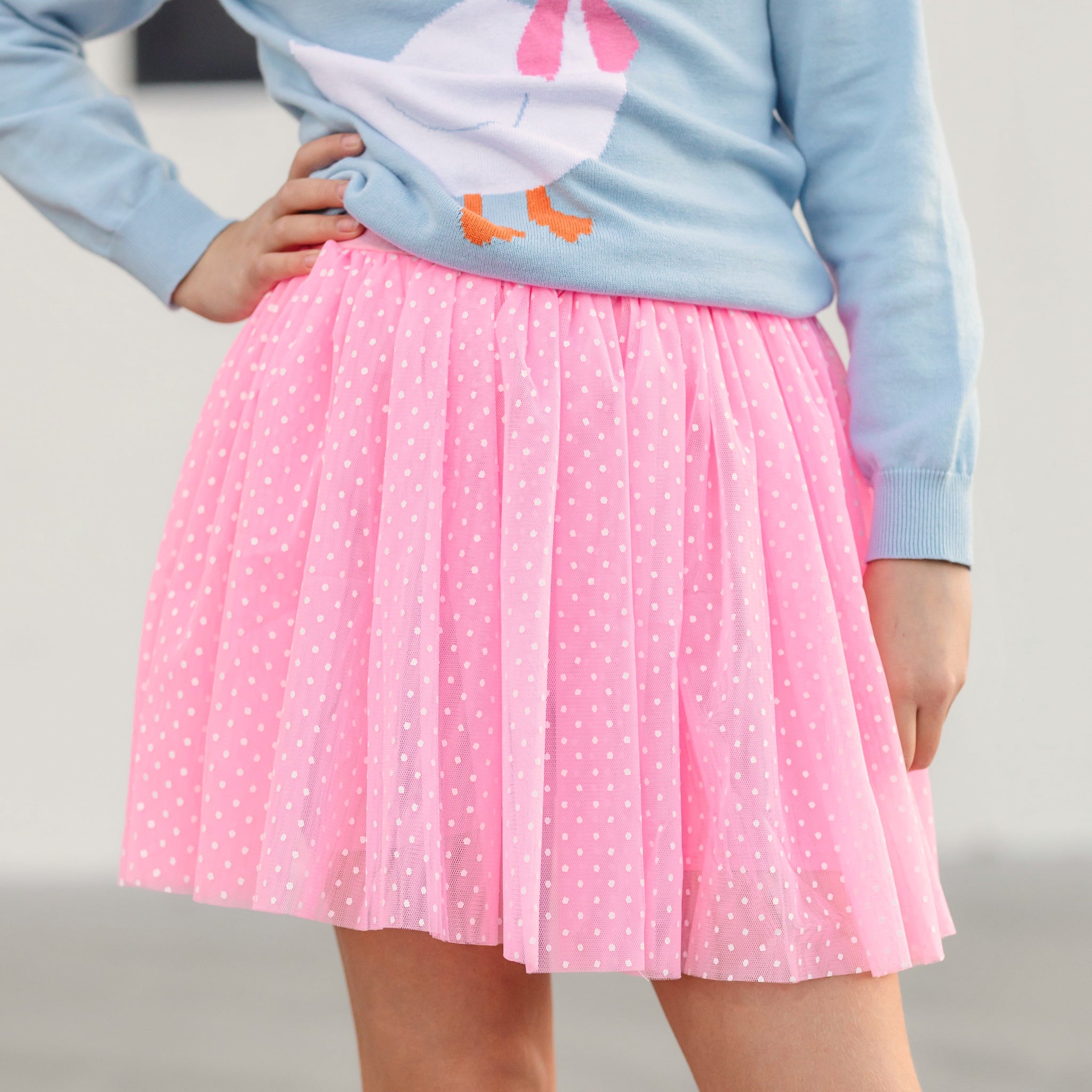 young girl wearing pink tulle skort with painted white dots paired with blue goose sweater