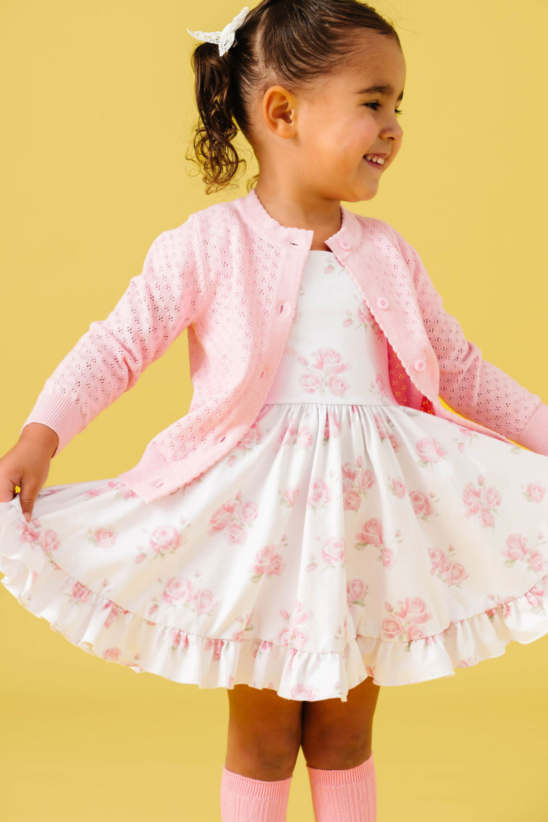 little girl in white twirl dress with pastel pink rose print paired with matching pink pointelle cardigan for spring