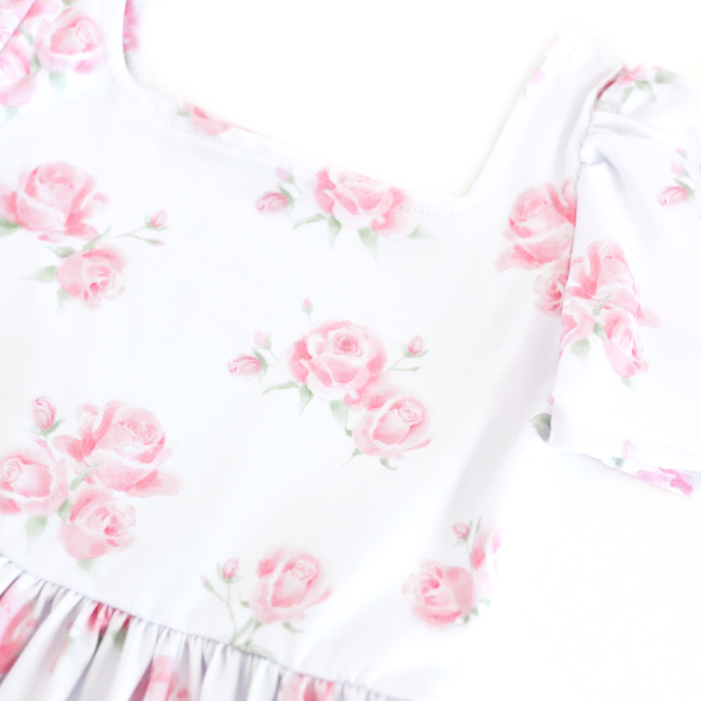 closeup of girls' white square neck twirl dress with soft pink roses in bloom