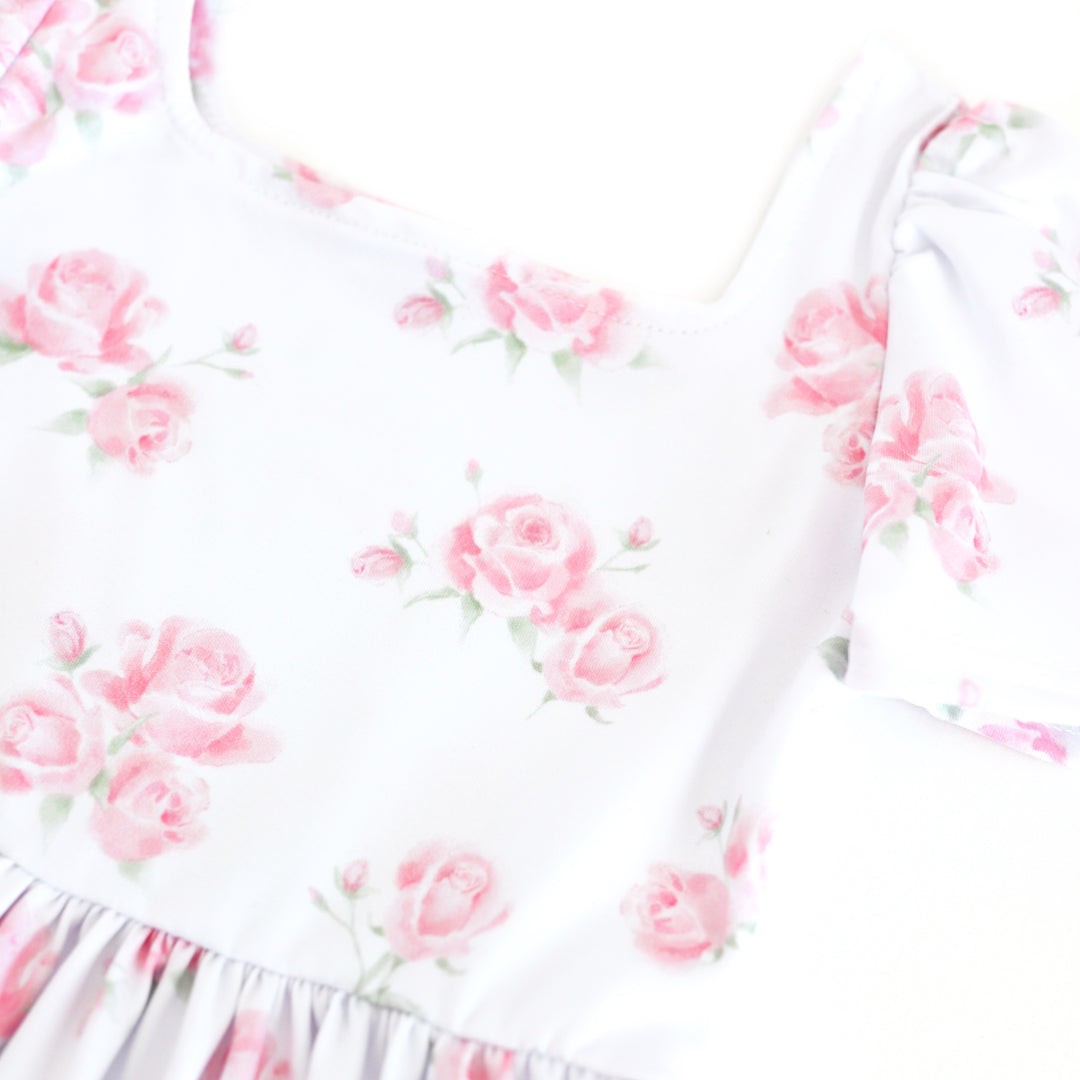 closeup of girls' white square neck twirl dress with soft pink roses in bloom