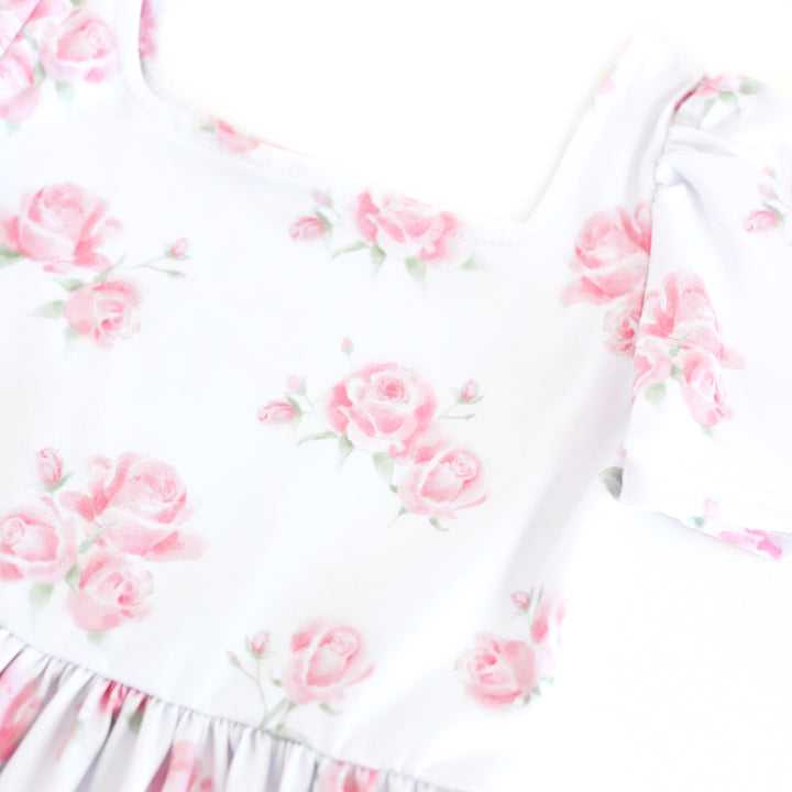 closeup of girls' white square neck twirl dress with soft pink roses in bloom