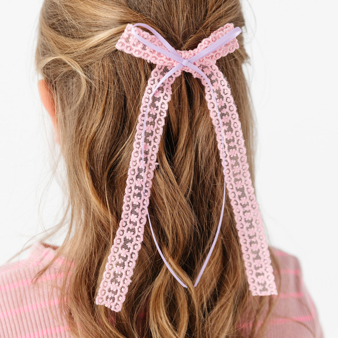 little girl in pink lace long tailed bow with purple satin ribbon overlay