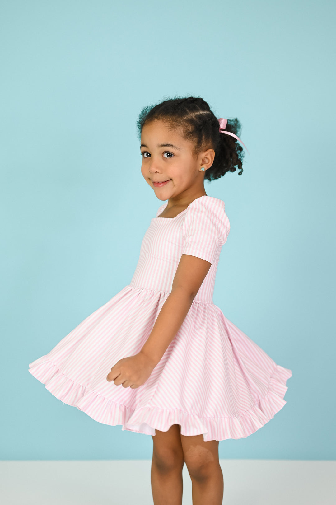 little girl twirling in light pink and white pinstripe twirl dress
