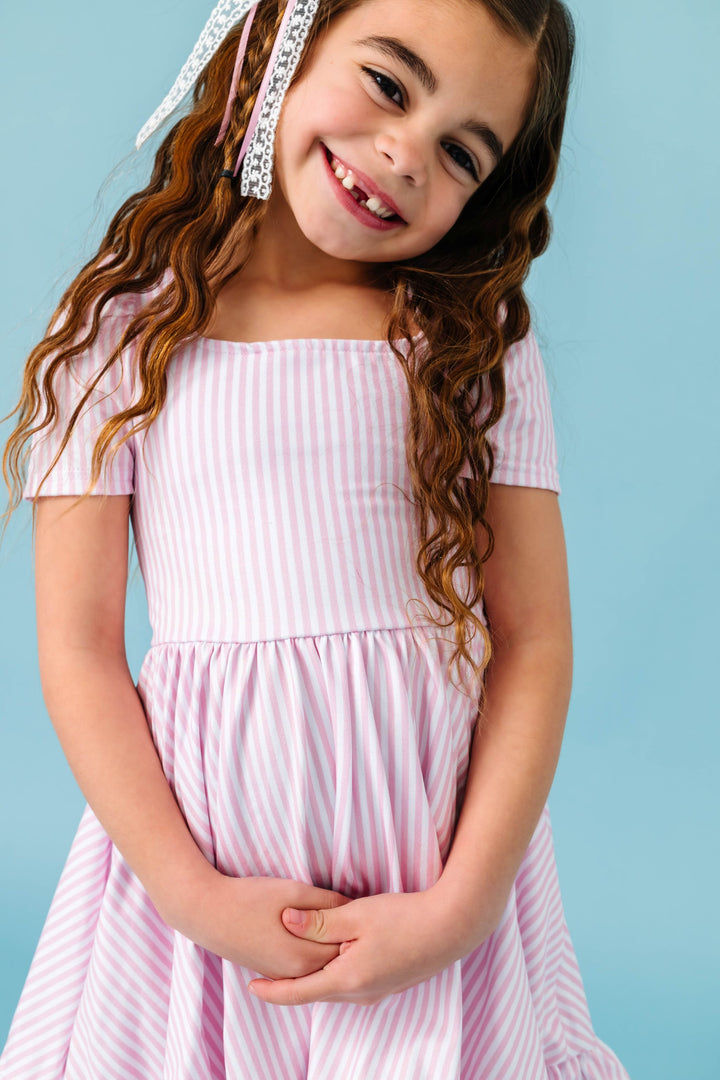 young girl in pastel pink and white pinstripe twirl dress for spring