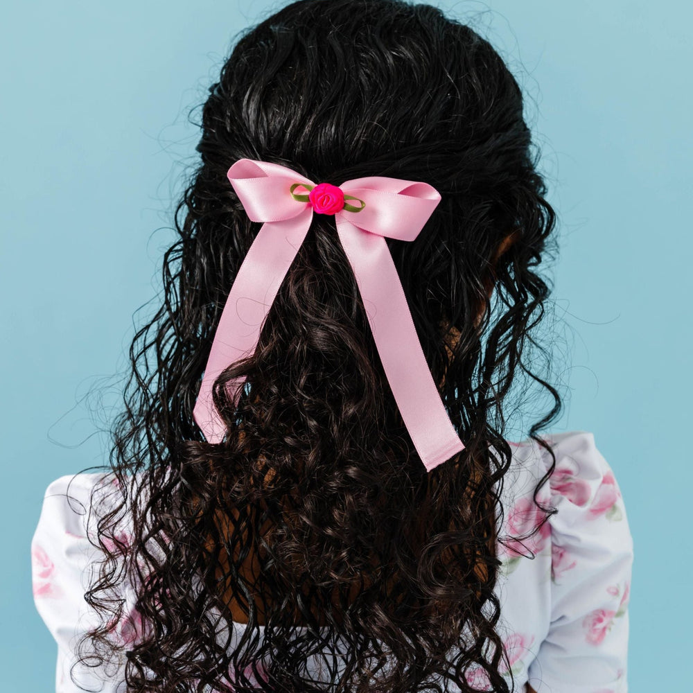 girl wearing pink rose dress and light pink satin hair bow with bright pink rosette detail 