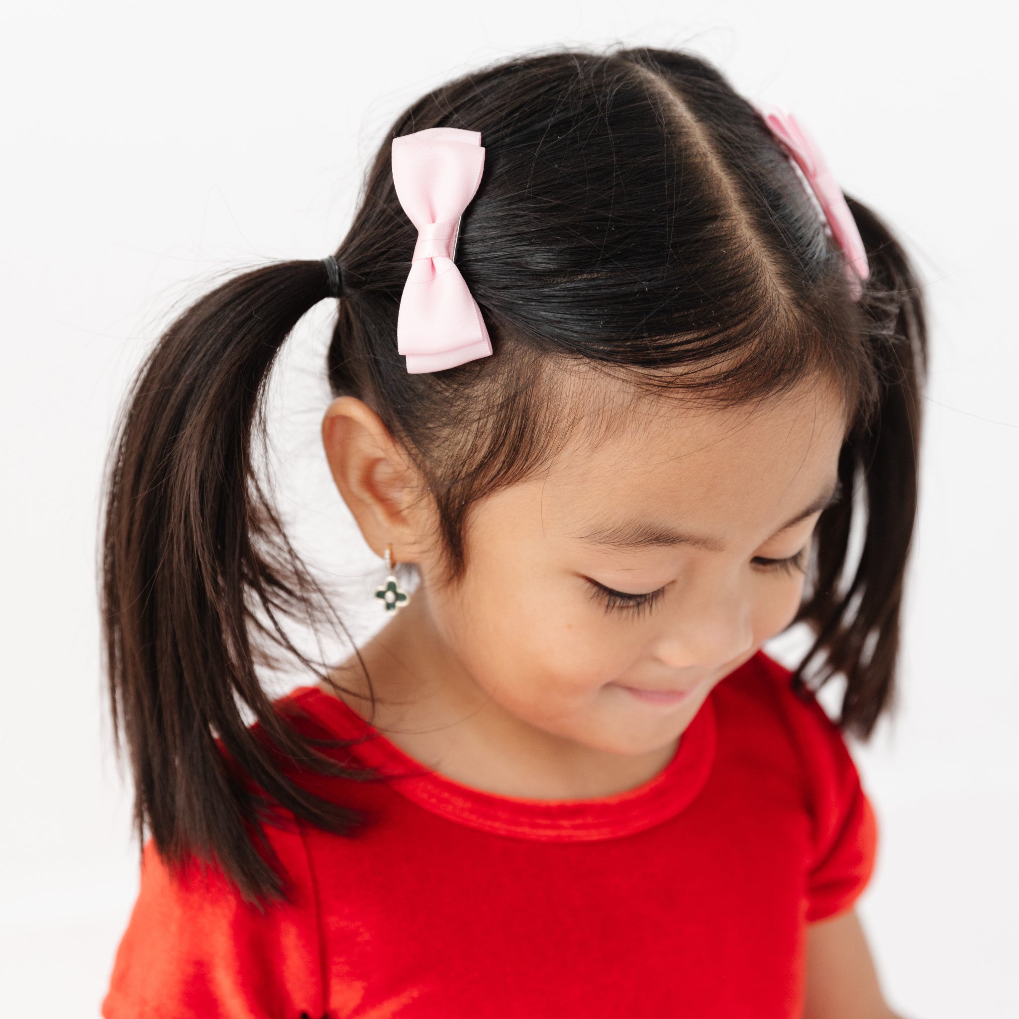 little girl in red velvet dress and light pink satin pigtail bows on clips