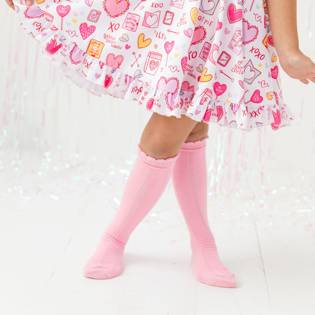 little girl in scalloped pink knee highs socks and matching class valentine inspired twirl dress