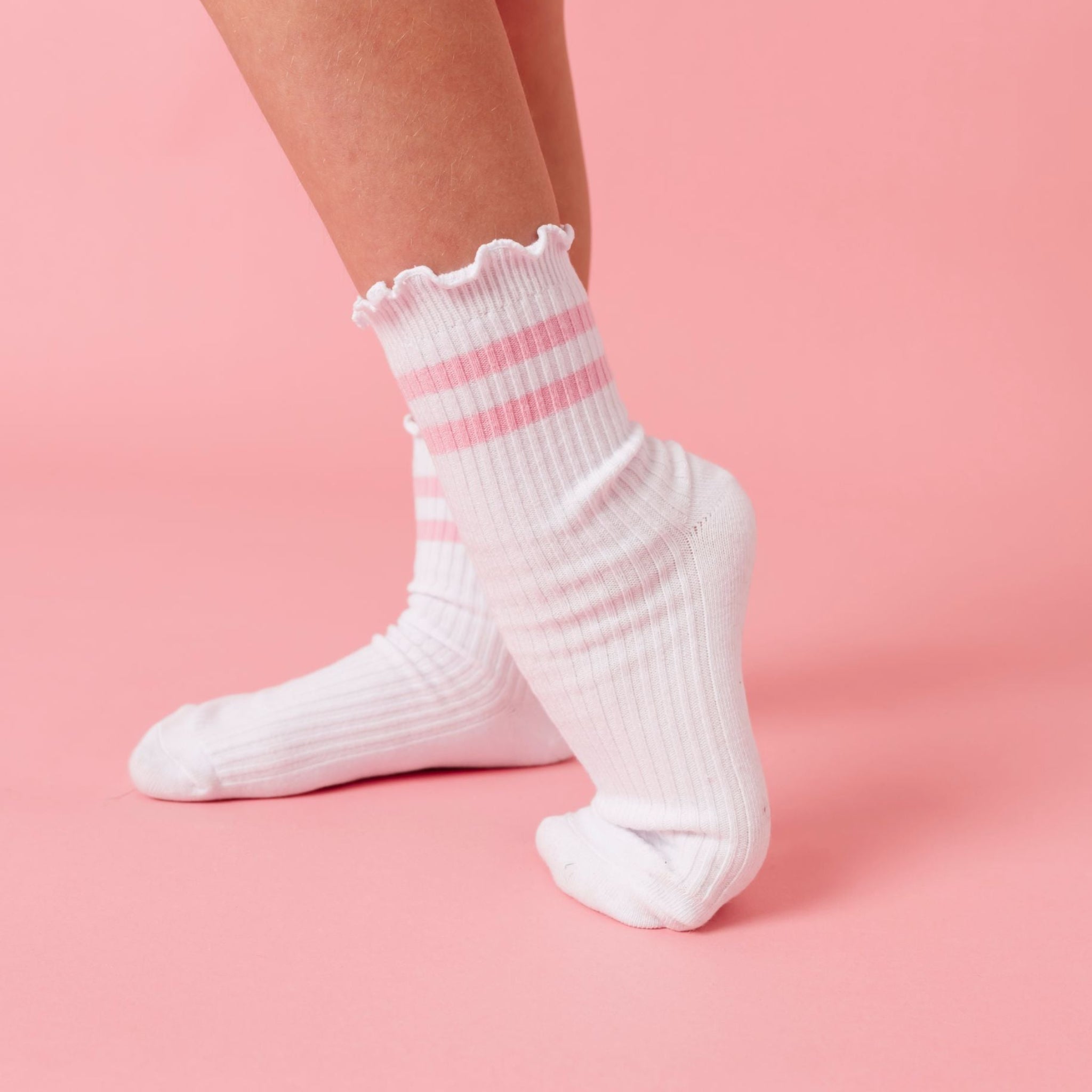 girl popping heel in white ribbed midi socks with lettuce trim and two light pink stripes at the ankle