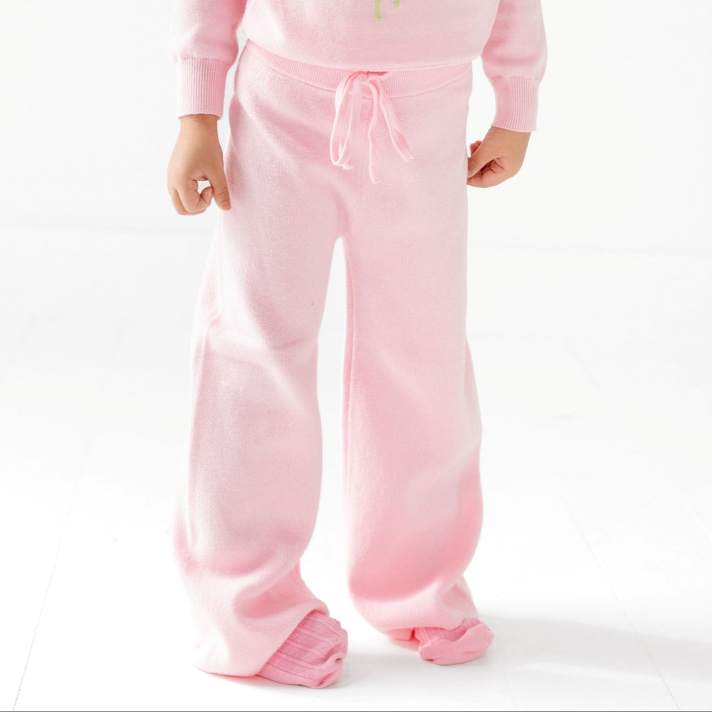 little girl wearing light pink cotton knit sweater pants with drawstring waistband and matching pink sweater and socks