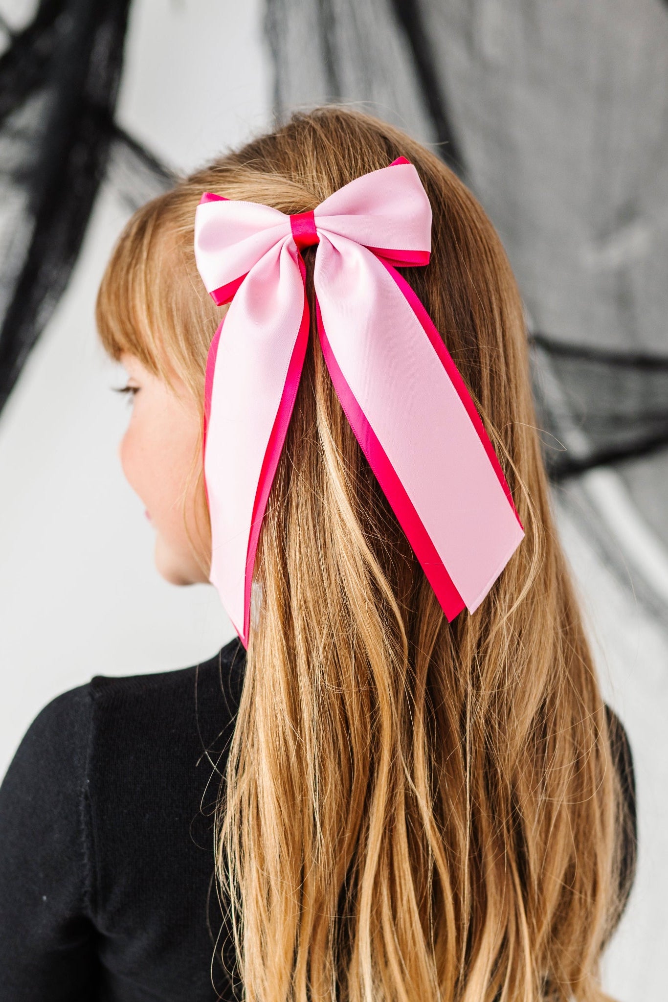 young girl in black and white Halloween sweater set with hot pink and light pink layered wide ribbon hair bow