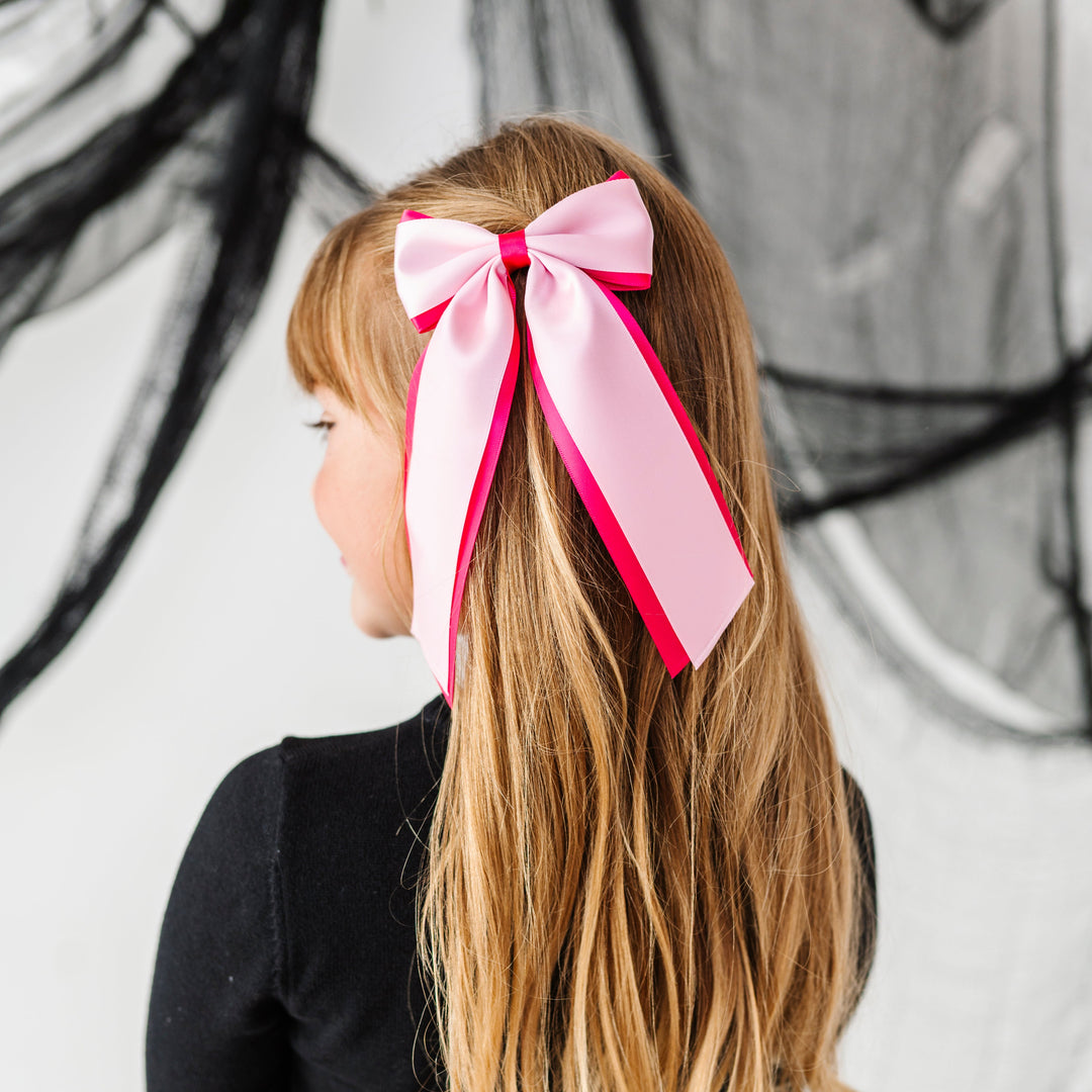 young girl in black and white Halloween sweater set with hot pink and light pink layered wide ribbon hair bow