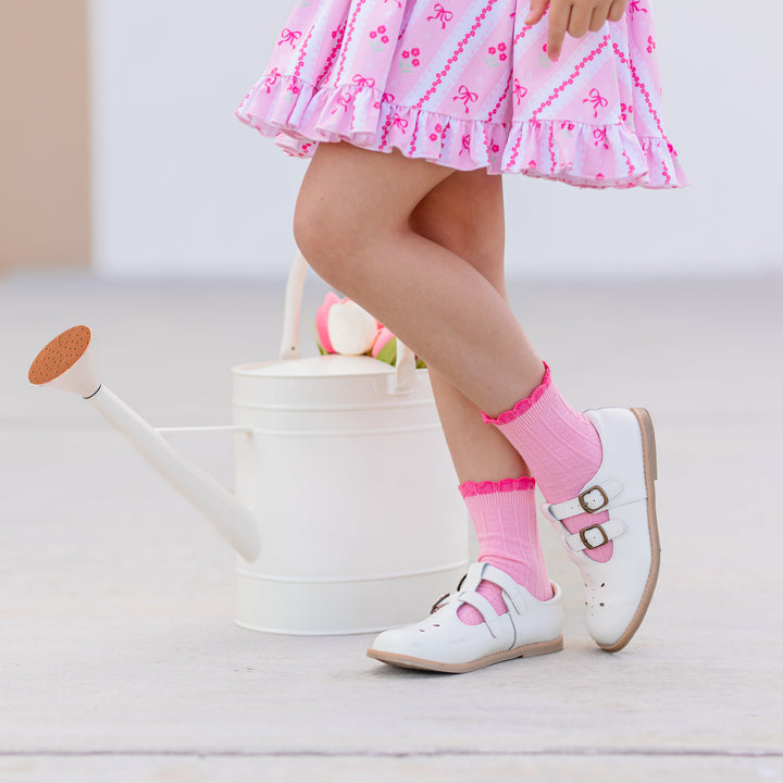 little girl in spring pink wallpaper print twirl dress paired with two-tone pink scalloped midi socks and white mary janes