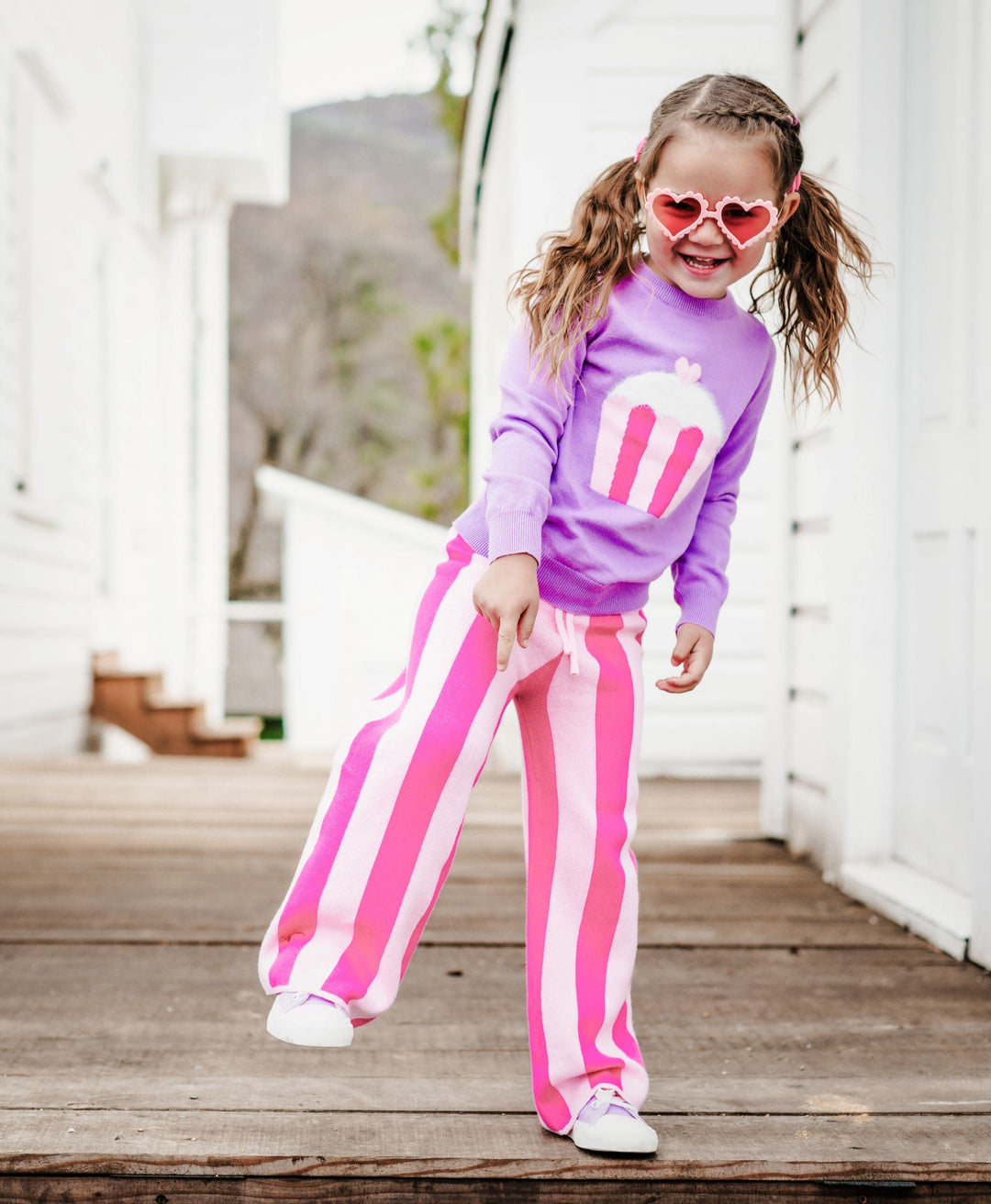 little girl in heart sunnies, lavender cupcake sweater and matching two tone pink striped sweater pants for Valentine's Day