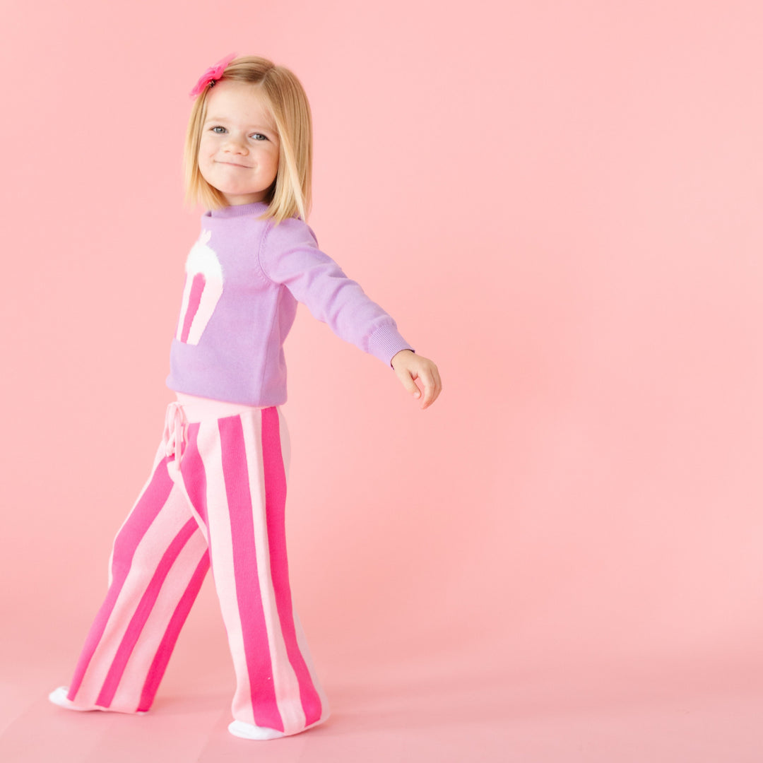 little girl walking in two tone pink striped sweater knit pants with matching lavender cupcake pullover and pink tutu bow on clip