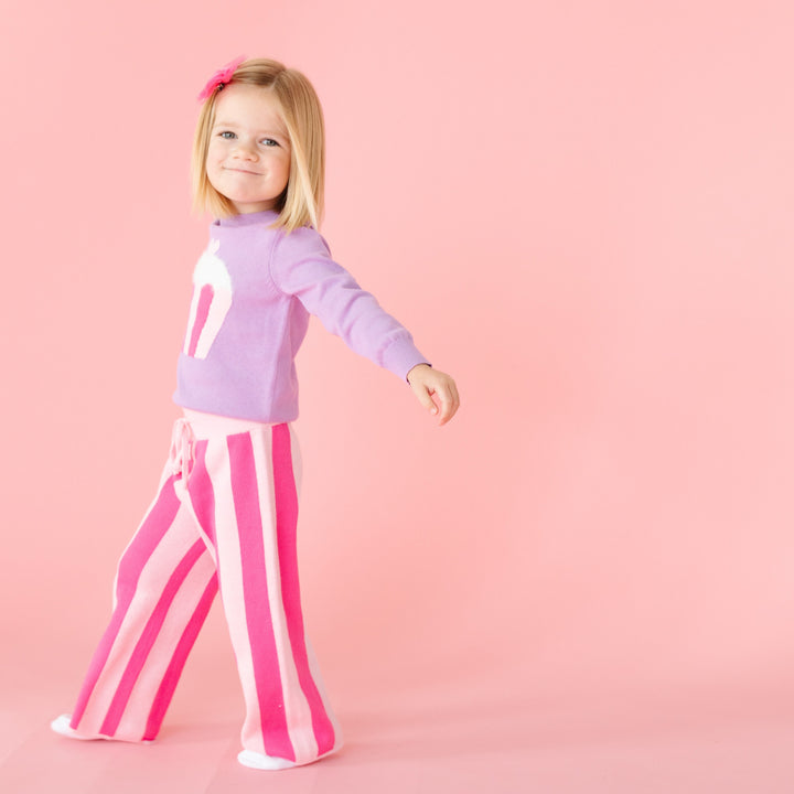 little girl walking in two tone pink striped sweater knit pants with matching lavender cupcake pullover and pink tutu bow on clip
