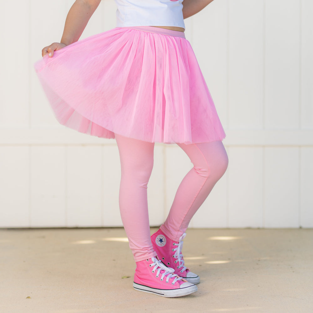 little girl in pink tulle skirt with stretchy cotton blend leggings attached and pink high tops