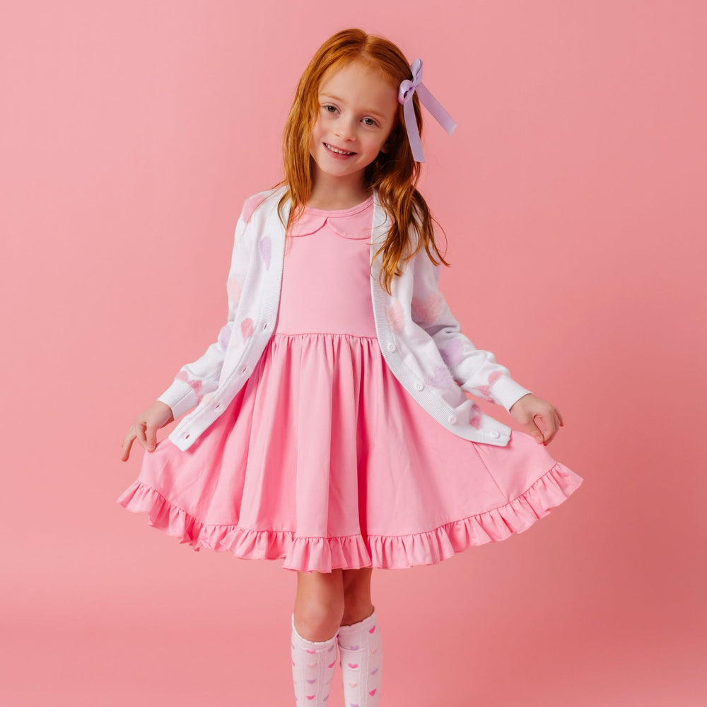 little girl in light pink collared cotton blend twirl dress paired with white fuzzy pastel heart cardigan and matching white with pastel heart knee socks for Valentine's day