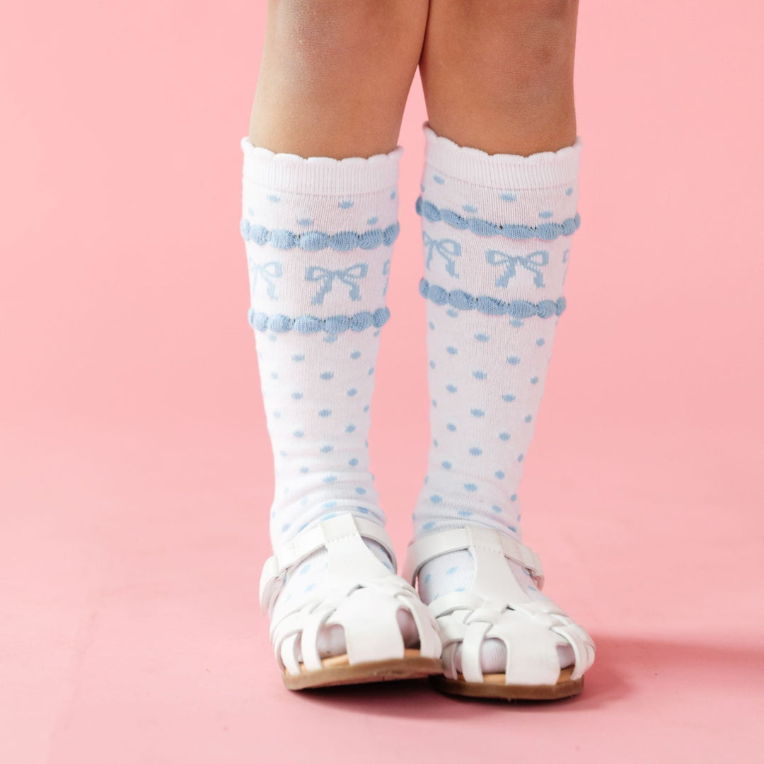 little girl in white with blue polka dot and bow print knee high socks for spring