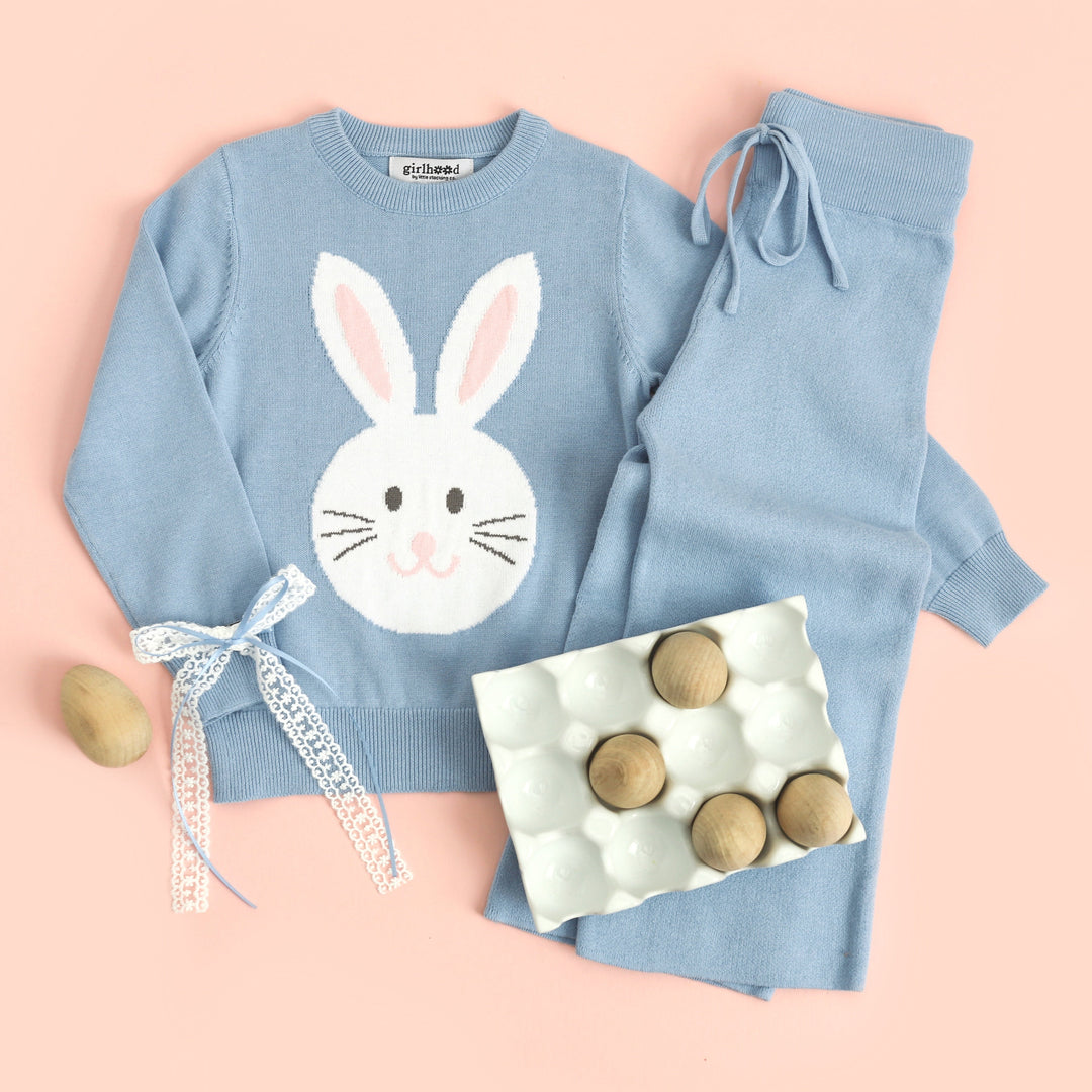 styled flat lay of blue cotton knit pullover sweater with bunny design and matching blue sweater pants and hair bow