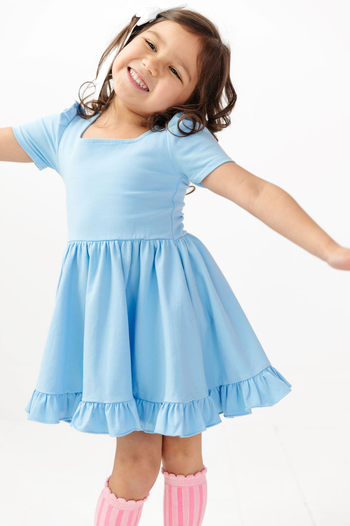 little girl in light blue cotton twirl dress with pink knee highs and white satin bow