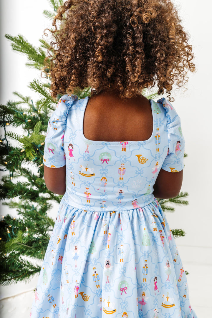 detail photo of square neck back of light blue nutcracker print twirl dress on little girl in front of Christmas tree