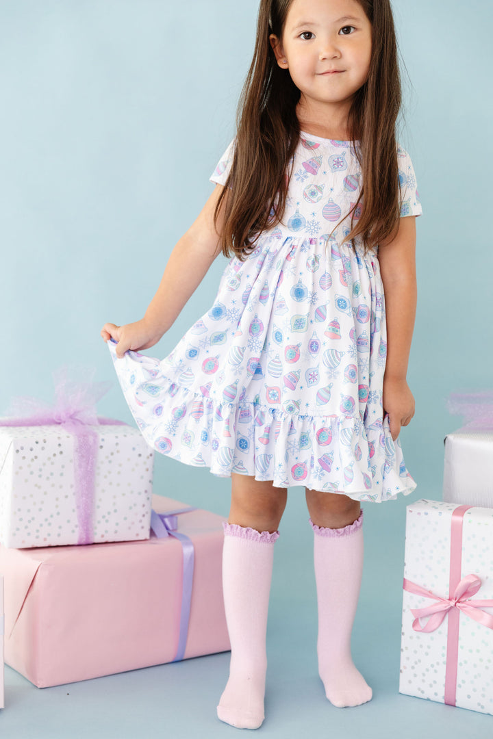 little girl in festive pastel ornament print twirl dress and matching light purple knee highs with lace