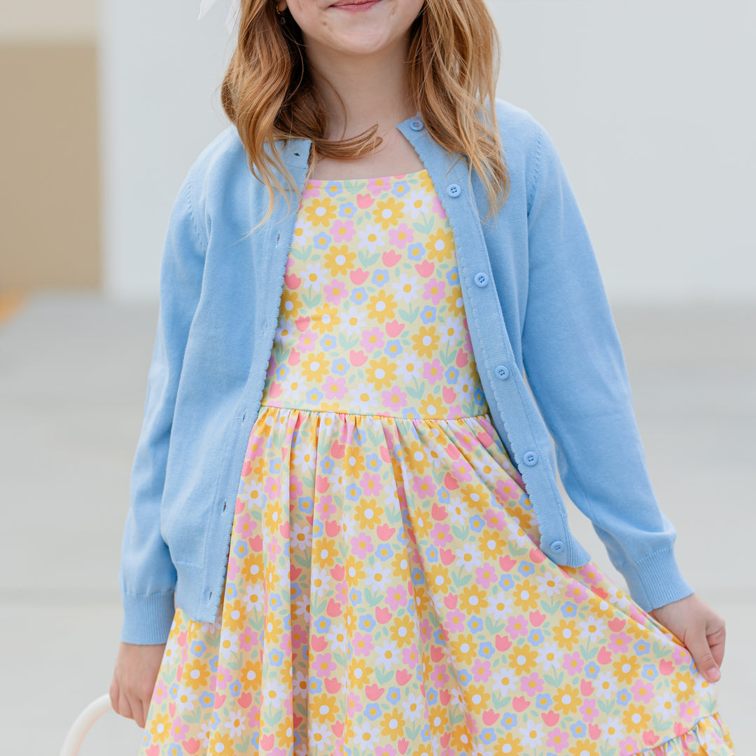 little girl in blue scallop trim cardigan and matching spring yellow floral twirl dress