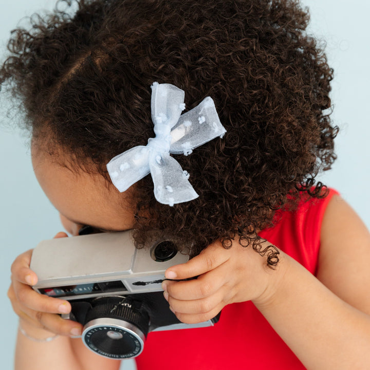 little girl with light blue sheer dot pigtail bow on clip and red dress