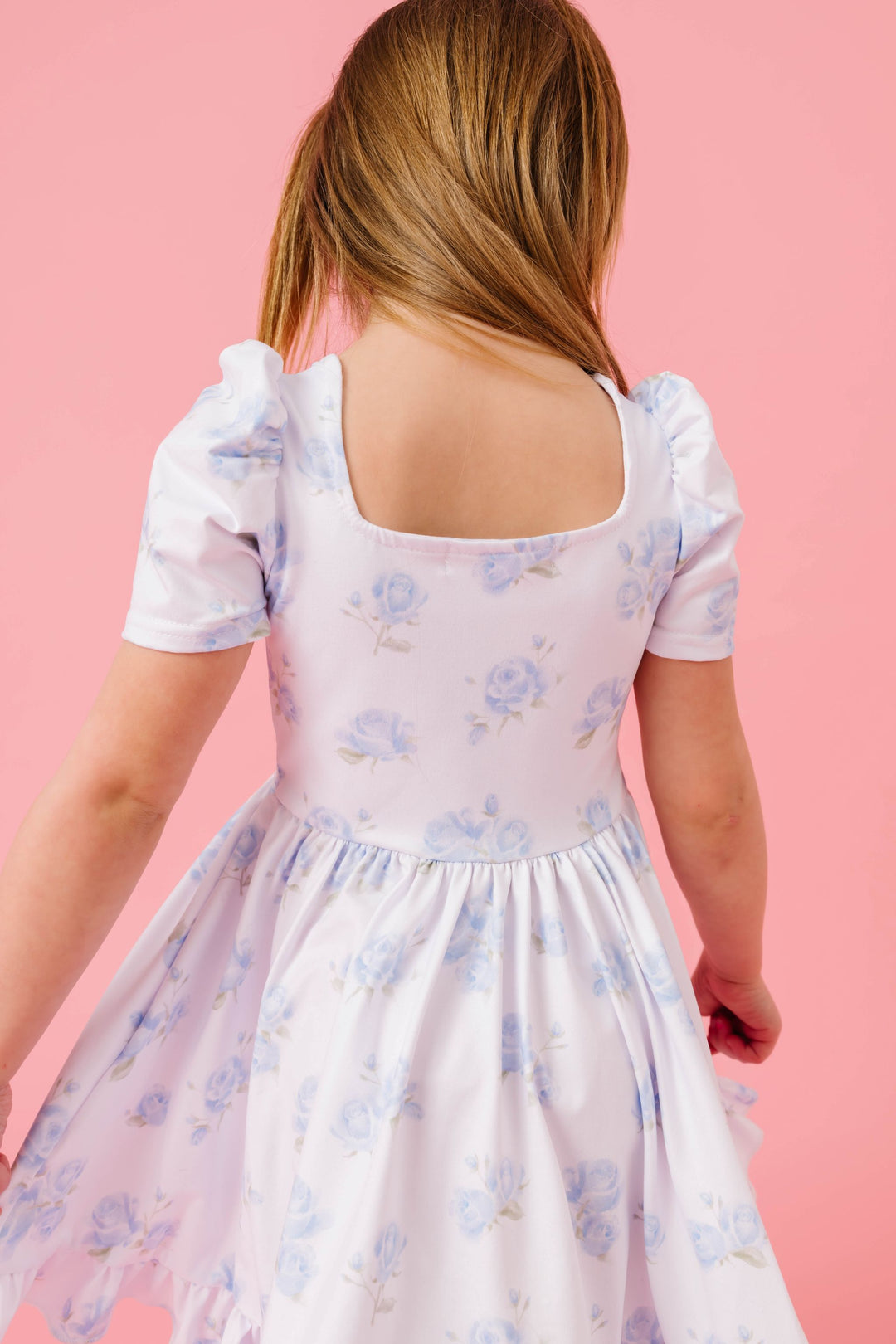 back view of little girl in square neck twirl dress with pastel blue rose print on white for spring