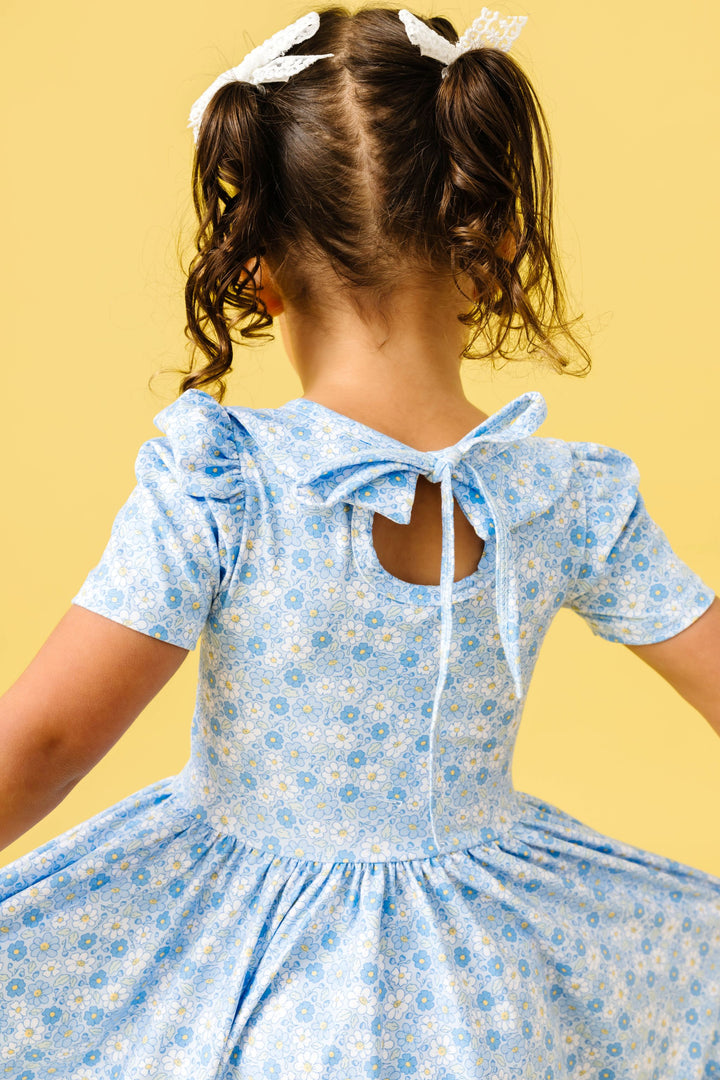 back view of little girl in spring blue micro floral twirl dress with keyhole tie back for spring