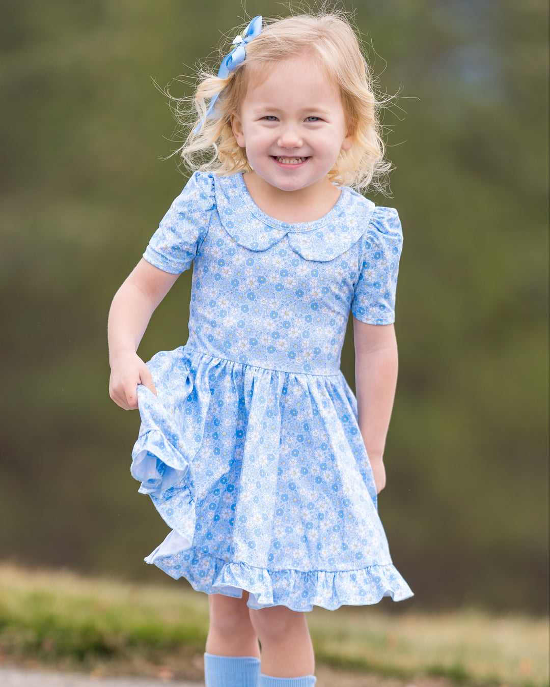 little girl in micro floral twirl dress with peter pan collar in shades of pastel blue, white and yellow with matching accessories
