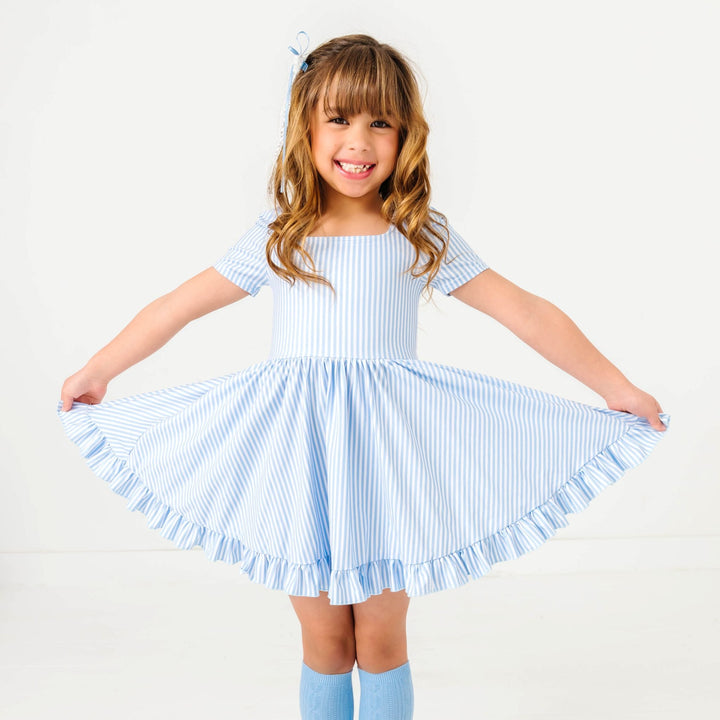 little girl in spring blue and white pinstripe twirl dress with matching blue cable knit knee socks
