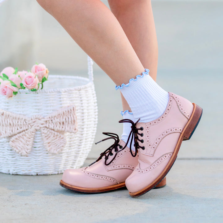 girl by Easter basket wearing white ribbed midi socks with blue lettuce trim and pink oxfords