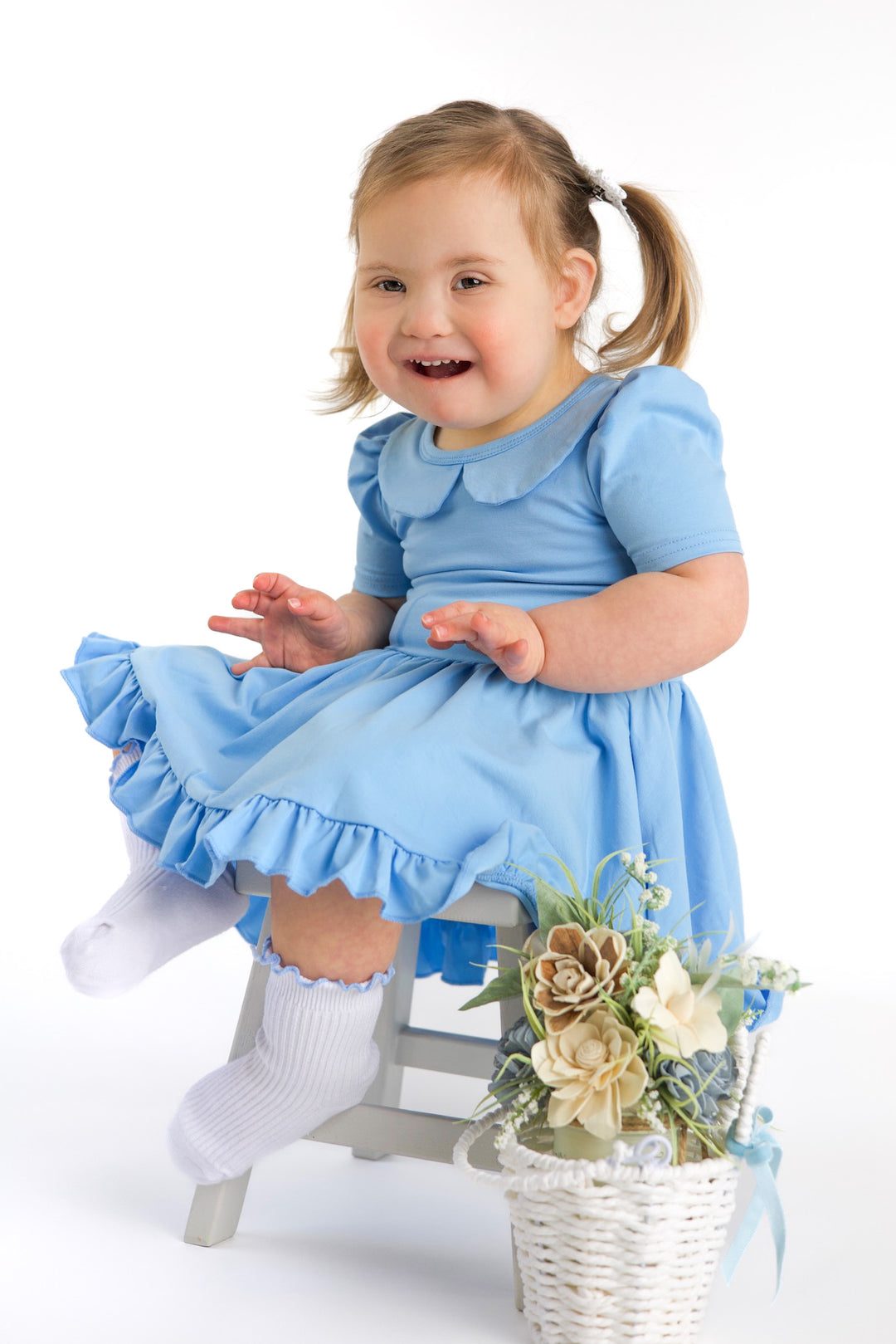 little girl sitting with flower basket in spring blue twirl dress with peter pan collar paired with white ribbed midi socks with light blue lettuce trim