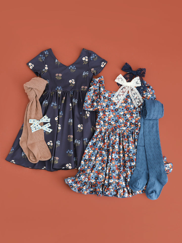 coordinating girls fall floral dresses in shades of blue paired with matching tights and lace hair bows