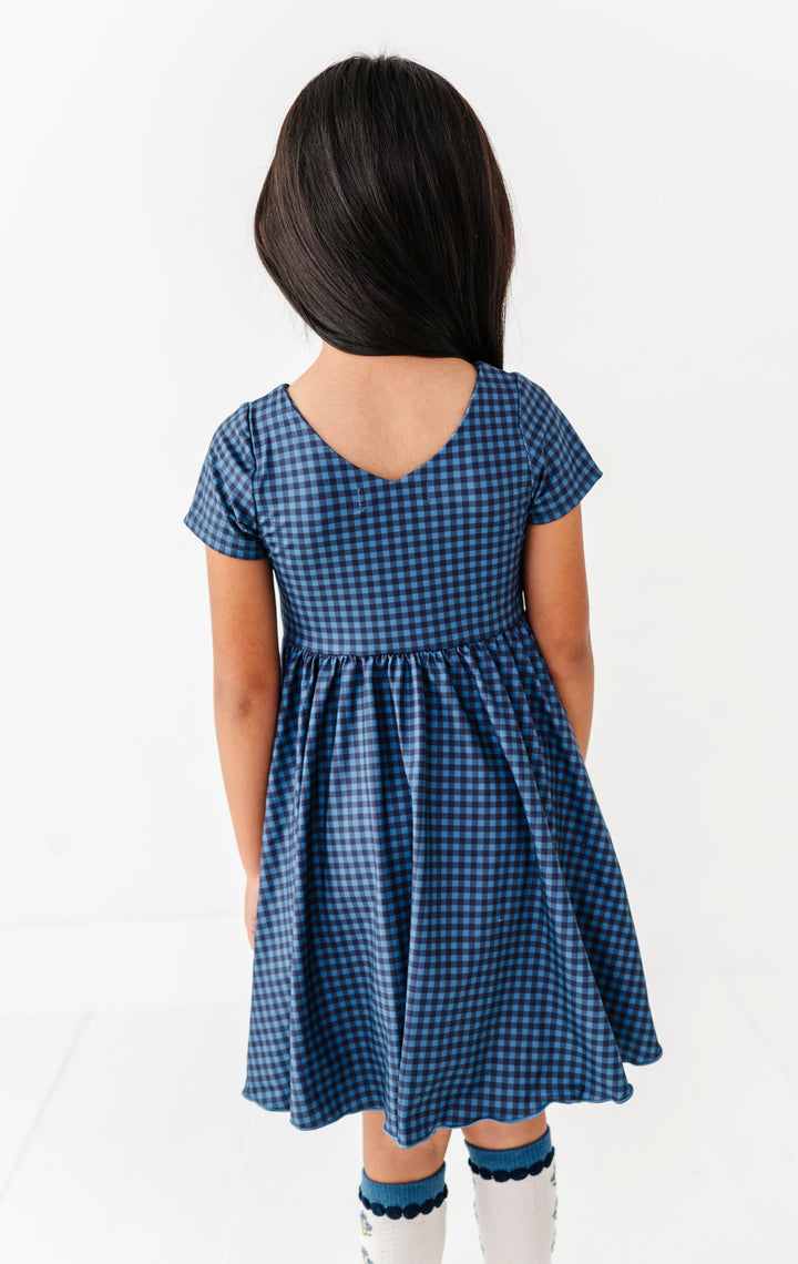 back detail photo of little girl in V-neck short sleeve gingham twirl dress in blue