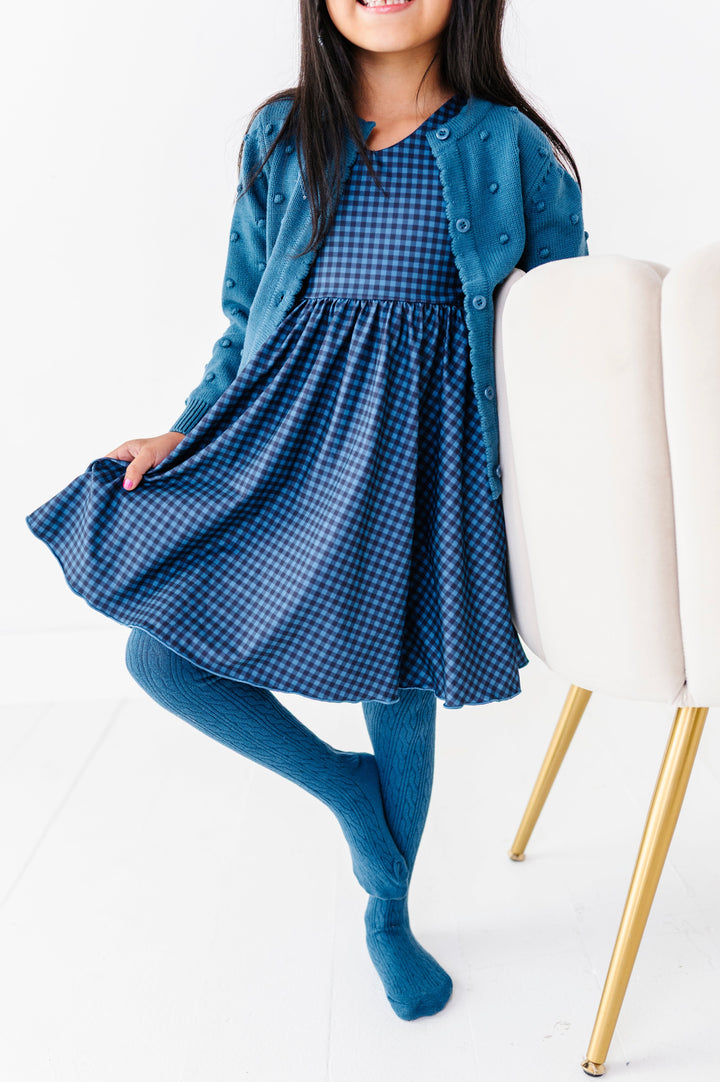girl in two-tone blue gingham twirl dress paired with matching blue cardigan and cable knit tights