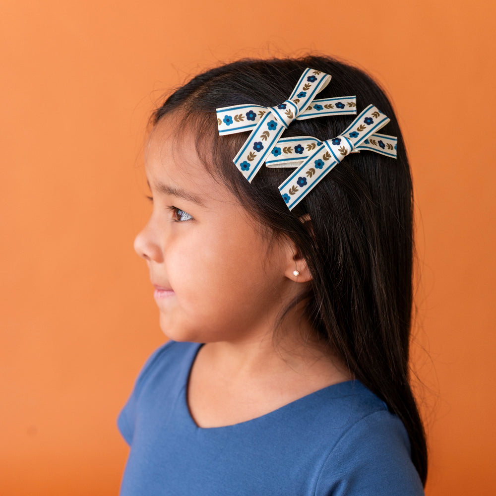 little girl with two blue and olive floral pigtail bows stacked as a side clip