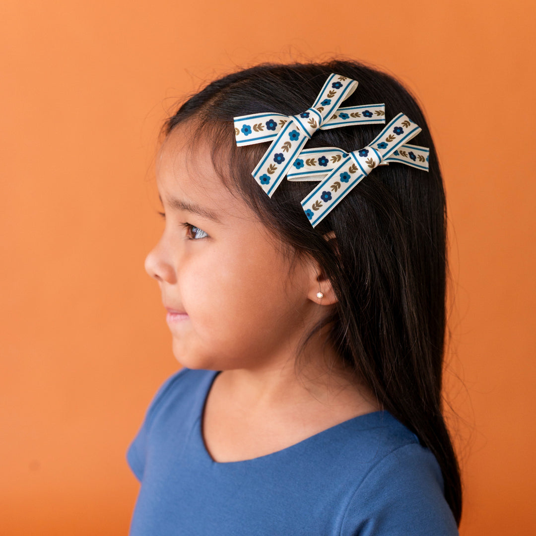 little girl with two blue and olive floral pigtail bows stacked as a side clip