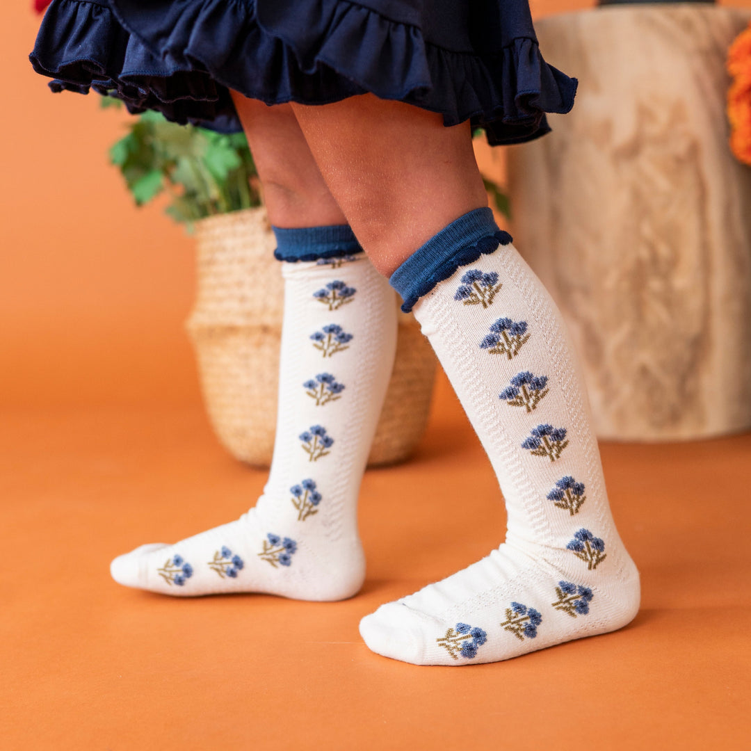 young girl in navy twirl dress paired with coordinating ivory and blue fall floral knee socks 