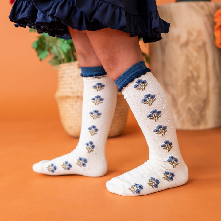 young girl in navy twirl dress paired with coordinating ivory and blue fall floral knee socks 