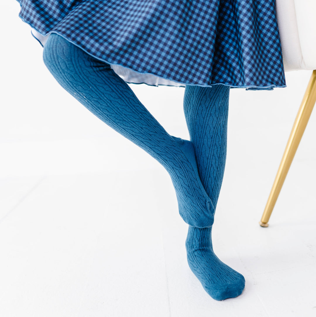 closeup of little girl in blue cable knit tights and matching gingham twirl dress for fall