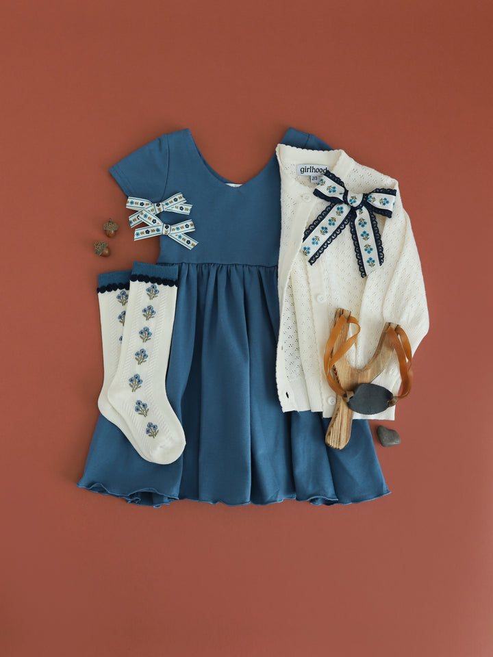 girls solid blue v-neck twirl dress paired with ivory pointelle cardigan and matching blue floral knee socks and bows