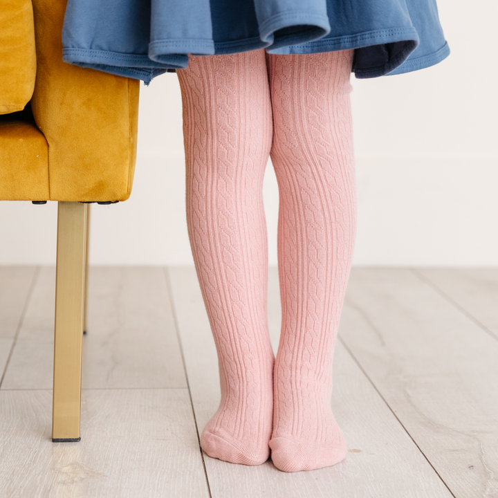 girl standing with blush cable knit tights and blue dress