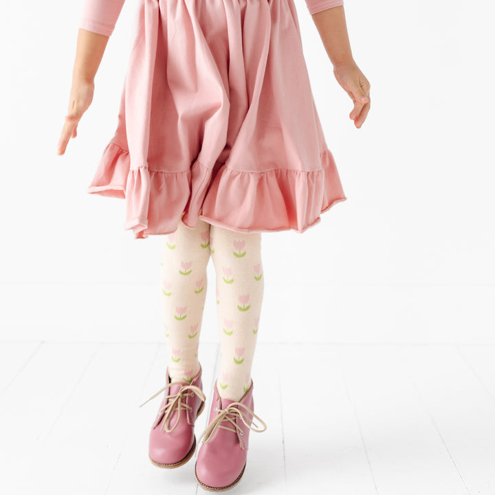 little girl wearing blush pink cotton blend twirl dress and cute tulip print knit tights