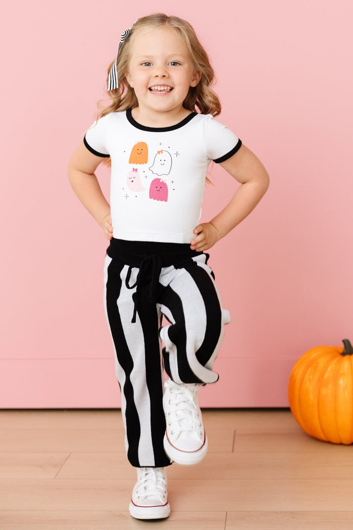 little girl skipping in black and white striped sweater pants with drawstring waistband paired with white fitted tee with four ghosts in bows