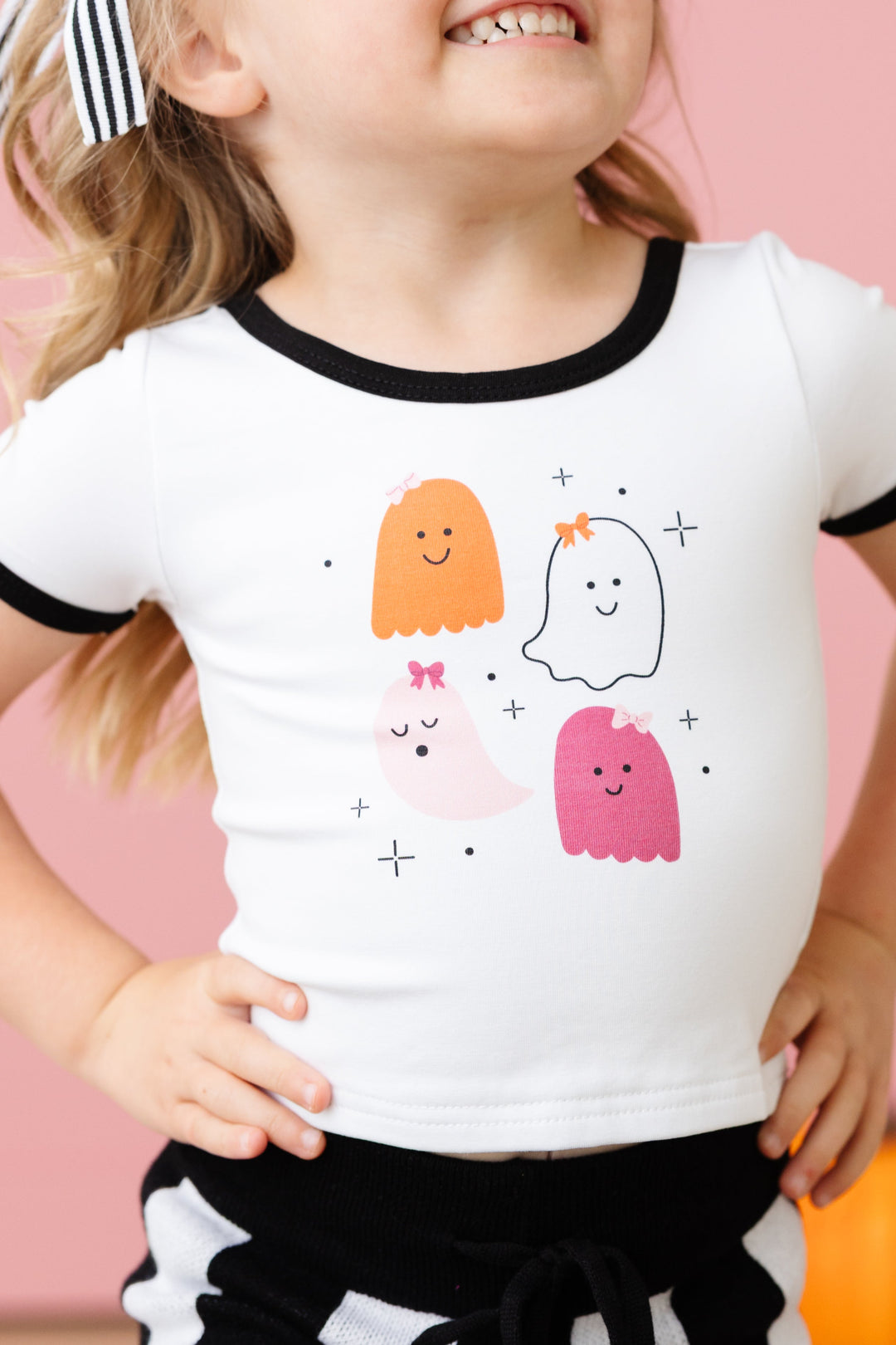 closeup of little girl in white cotton spandex blend fitted top with black binding and Halloween design with four ghosts in bows