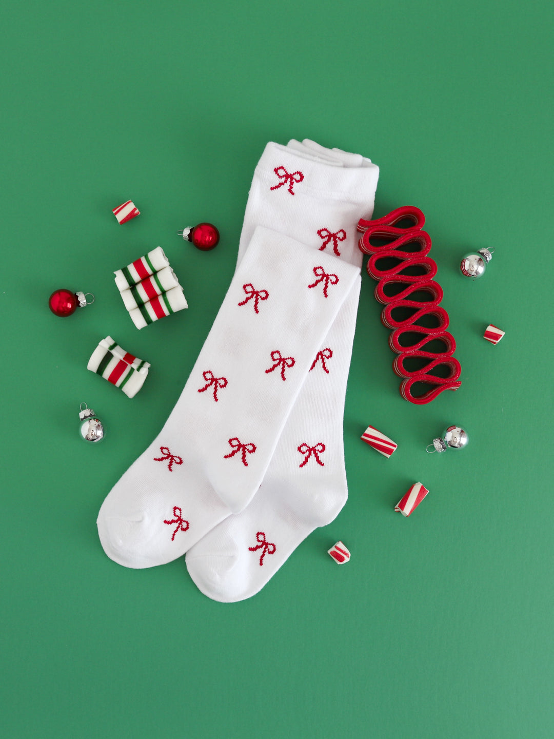 flat lay photo of girls' white knit tights with red bow design for Christmas
